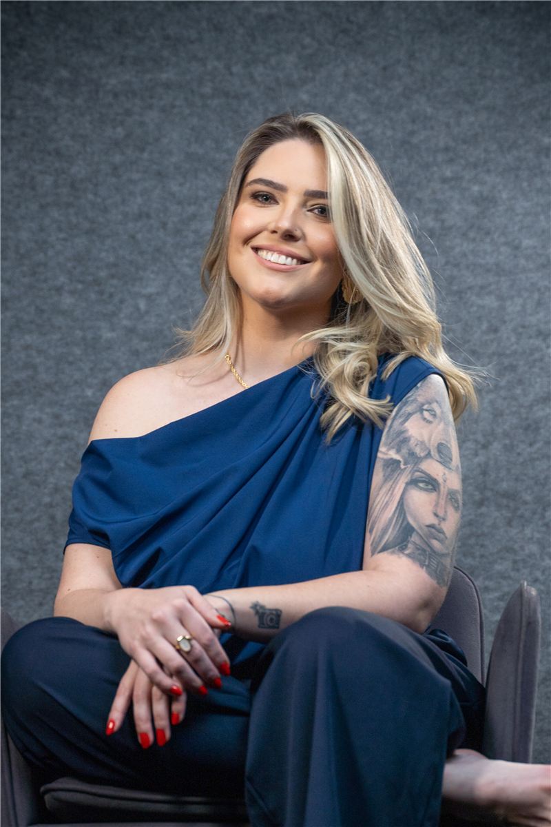Raphaela Spellmeier sentada, de blusa azul, sorrindo