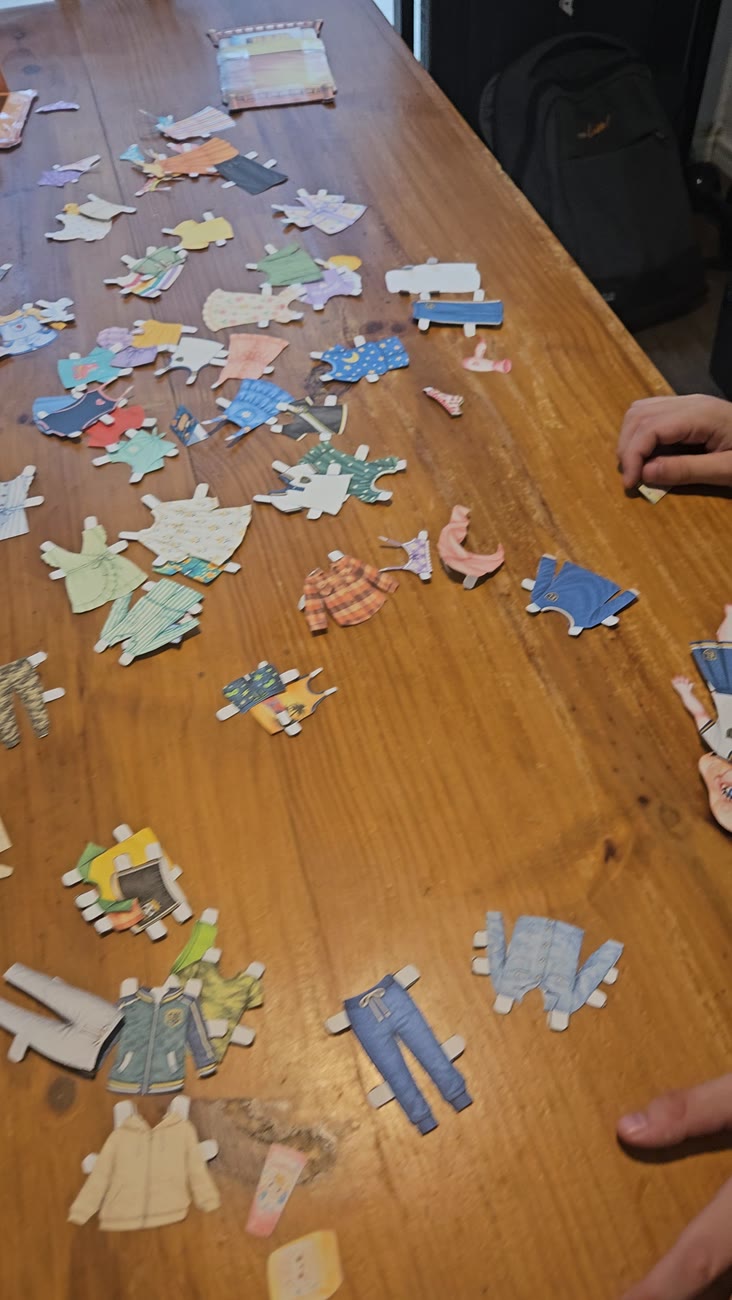 Mesa cheia de roupinhas recortadas durante a brincadeira